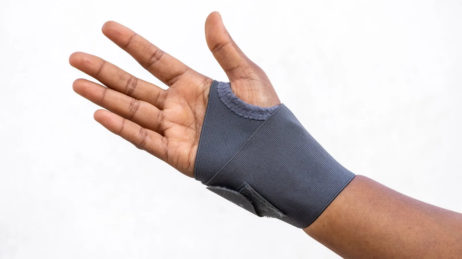 An open hand wearing a plain grey fabric wrist support against a white background